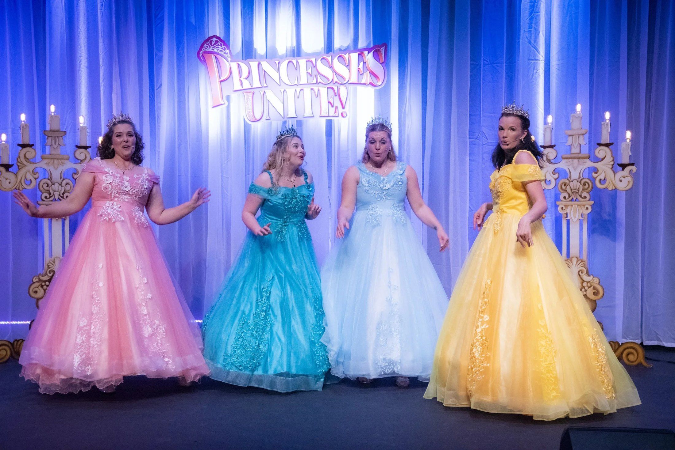 Four princesses in ball gowns on stage in Princesses Unite!